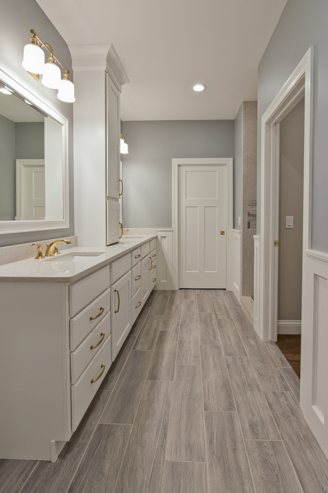This is an example of a traditional ensuite bathroom in Other with raised-panel cabinets, white cabinets, grey walls, porcelain flooring, a submerged sink, engineered stone worktops, grey floors, white worktops, double sinks, a built in vanity unit and wainscoting.