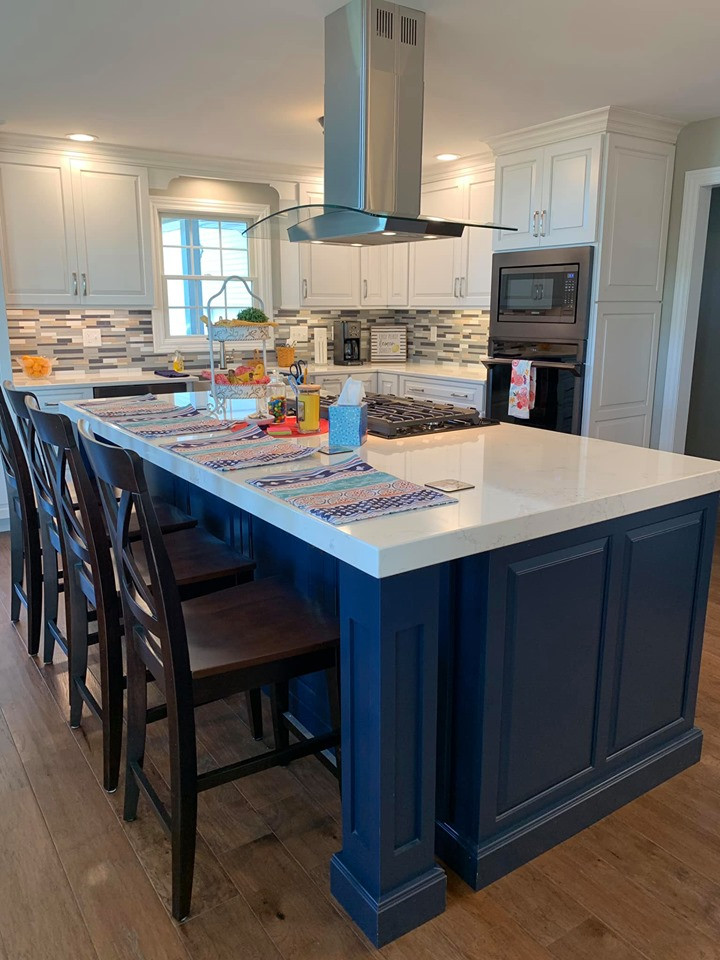 Design ideas for a mid-sized country l-shaped eat-in kitchen in Chicago with a farmhouse sink, raised-panel cabinets, blue cabinets, quartz benchtops, multi-coloured splashback, medium hardwood floors, brown floor and white benchtop.