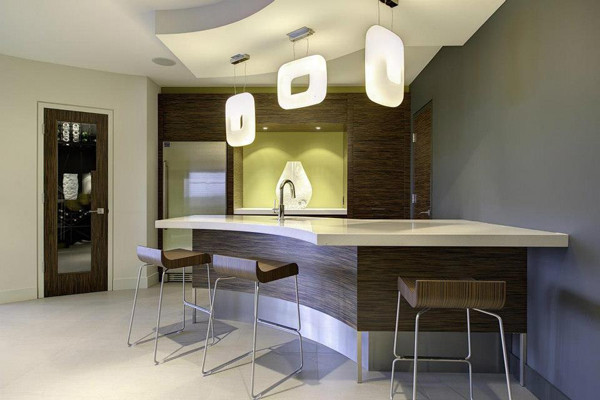 Photo of a large modern galley wet bar in Other with an undermount sink, flat-panel cabinets, medium wood cabinets, solid surface benchtops, green splashback, carpet, white floor and white benchtop.