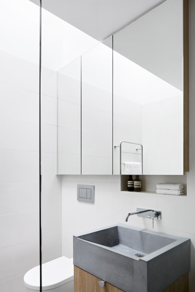 Inspiration for a small contemporary master bathroom in Melbourne with open cabinets, grey cabinets, a curbless shower, a wall-mount toilet, ceramic tile, white walls, ceramic floors, a wall-mount sink, concrete benchtops, grey floor, an open shower and grey benchtops.