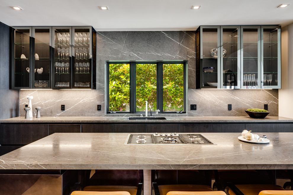 This is an example of a large contemporary single-wall open plan kitchen in Miami with flat-panel cabinets, blue cabinets, grey splashback, stone slab splashback, black appliances, light hardwood floors, with island, beige floor and beige benchtop.