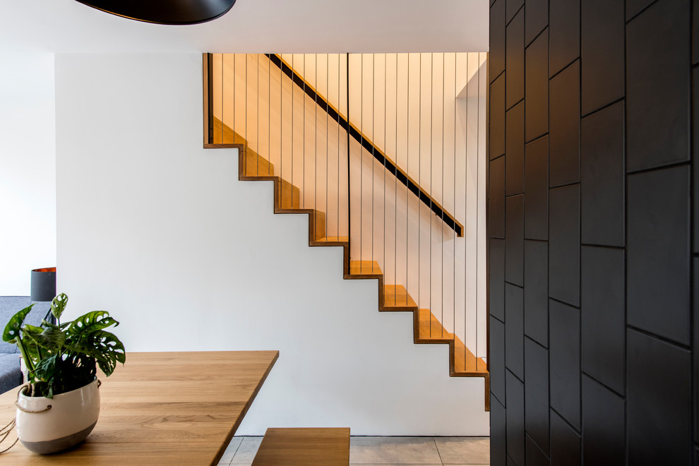 Inspiration for a small contemporary wood straight staircase in London with wood risers and metal railing.