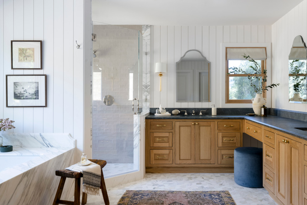 Пример оригинального дизайна: огромная главная ванная комната в стиле кантри с синими фасадами, душем в нише, унитазом-моноблоком, белой плиткой, белыми стенами, полом из известняка, накладной раковиной, мраморной столешницей, серым полом, душем с распашными дверями, белой столешницей, сиденьем для душа, тумбой под одну раковину, встроенной тумбой и фасадами с утопленной филенкой