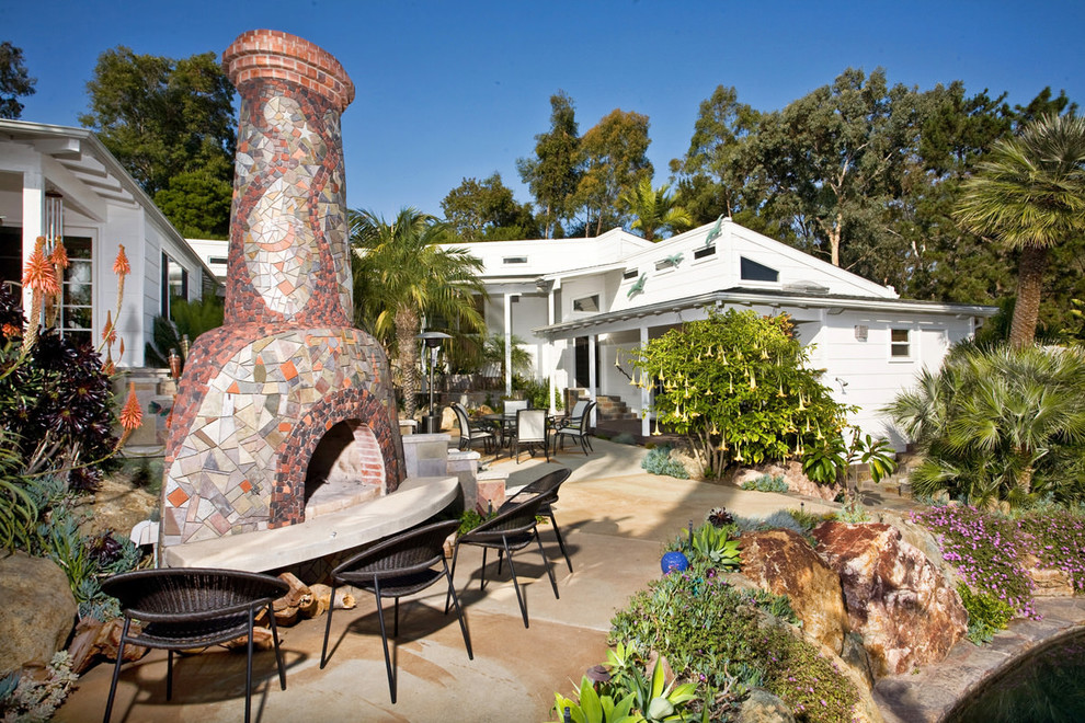 This is an example of a mid-sized tropical partial sun backyard concrete paver landscaping in San Diego with a fire pit.