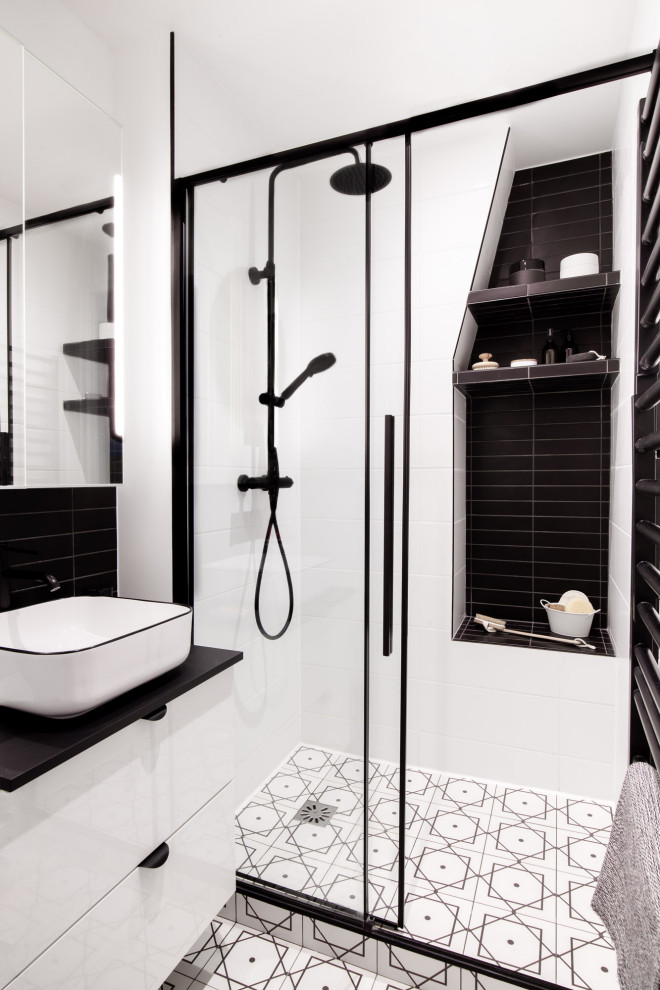 パリにある高級な中くらいなモダンスタイルのおしゃれなマスターバスルーム (白いキャビネット、ダブルシャワー、分離型トイレ、白いタイル、白い壁、セラミックタイルの床、オーバーカウンターシンク、白い床、引戸のシャワー、黒い洗面カウンター、洗面台1つ、フローティング洗面台) の写真