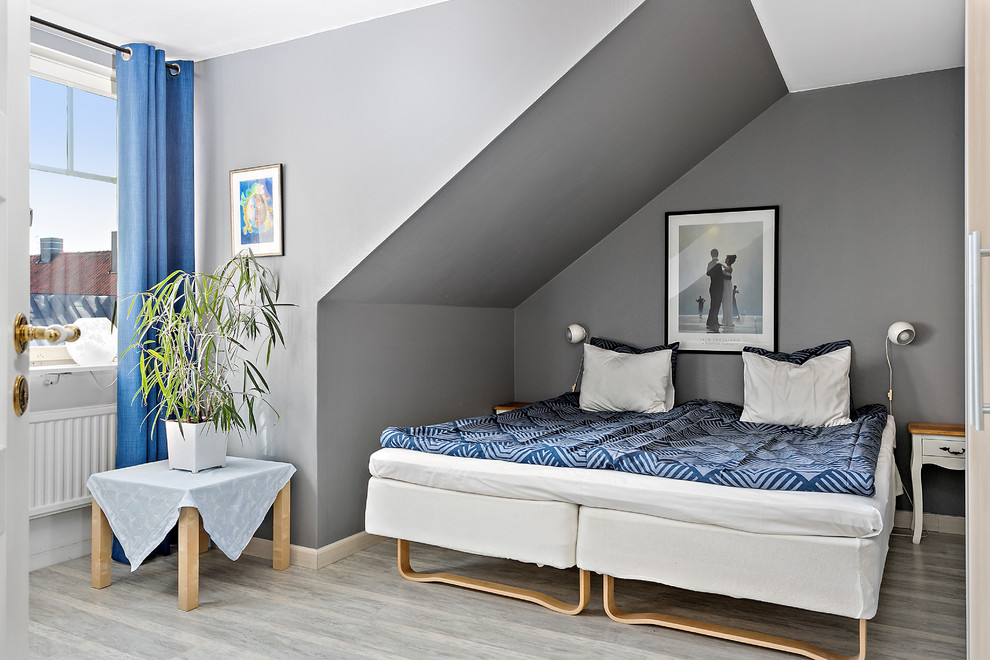 Photo of a scandinavian guest bedroom in Other with grey walls, light hardwood floors and grey floor.