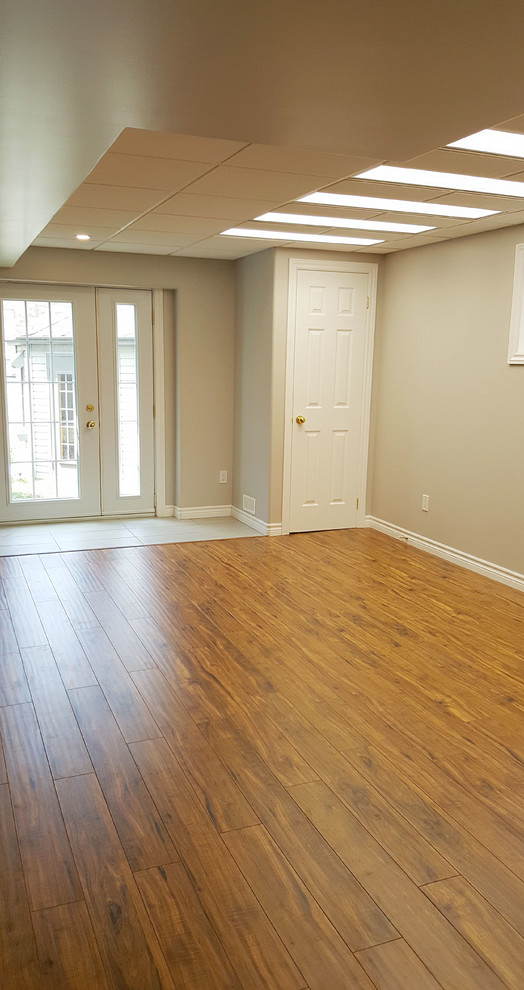 Inspiration for a large transitional walk-out laminate floor and brown floor basement remodel in Toronto