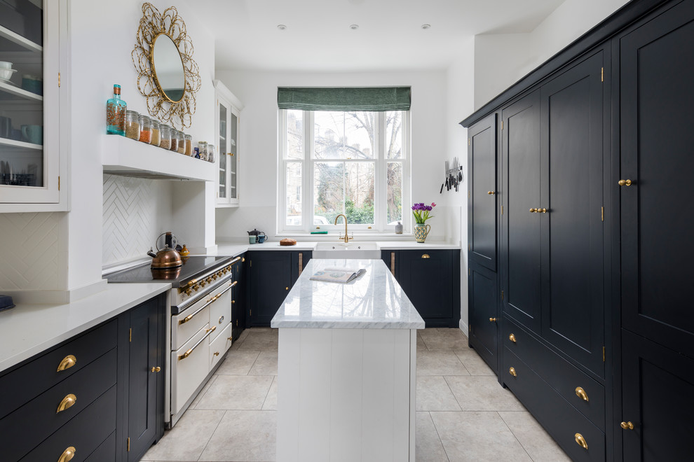 Design ideas for a transitional galley separate kitchen in London with shaker cabinets, black cabinets, marble benchtops, white splashback, black appliances, with island, beige floor, a farmhouse sink and subway tile splashback.