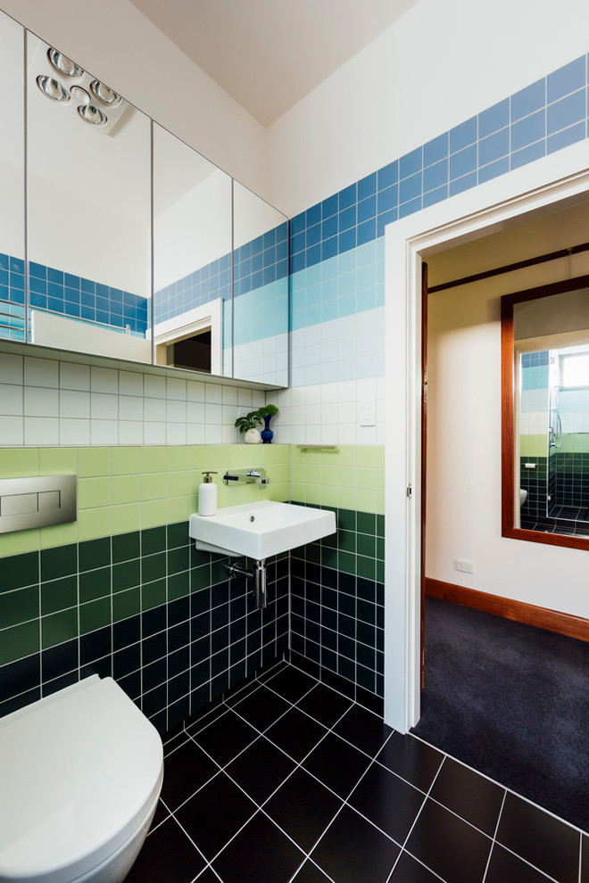 This is an example of a small contemporary master bathroom in Hobart with glass-front cabinets, medium wood cabinets, an alcove shower, a one-piece toilet, green tile, ceramic tile, blue walls, light hardwood floors, a wall-mount sink, brown floor and a hinged shower door.