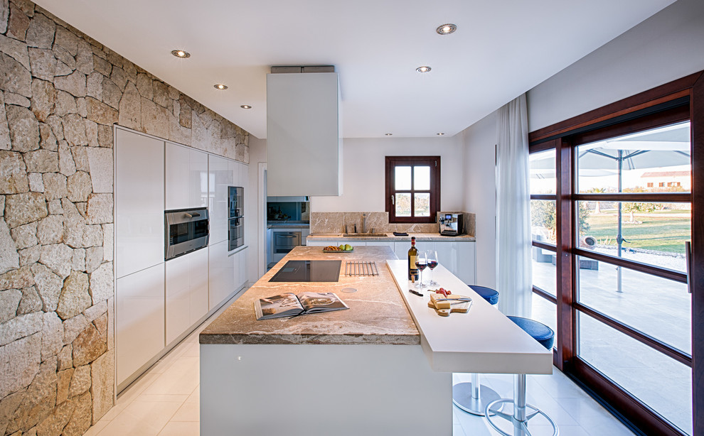 Mid-sized mediterranean l-shaped separate kitchen in Palma de Mallorca with a single-bowl sink, flat-panel cabinets, white cabinets, with island, marble benchtops, white splashback and stainless steel appliances.