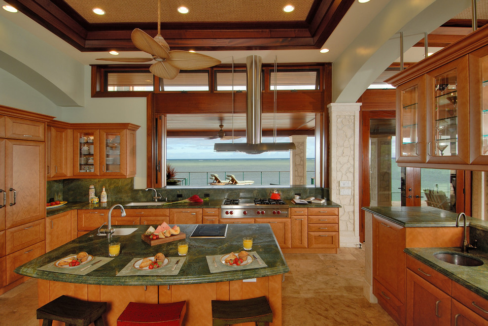 Example of a large island style u-shaped travertine floor and beige floor kitchen design in Hawaii with an undermount sink, medium tone wood cabinets, granite countertops, green backsplash, stone slab backsplash, stainless steel appliances, an island and shaker cabinets