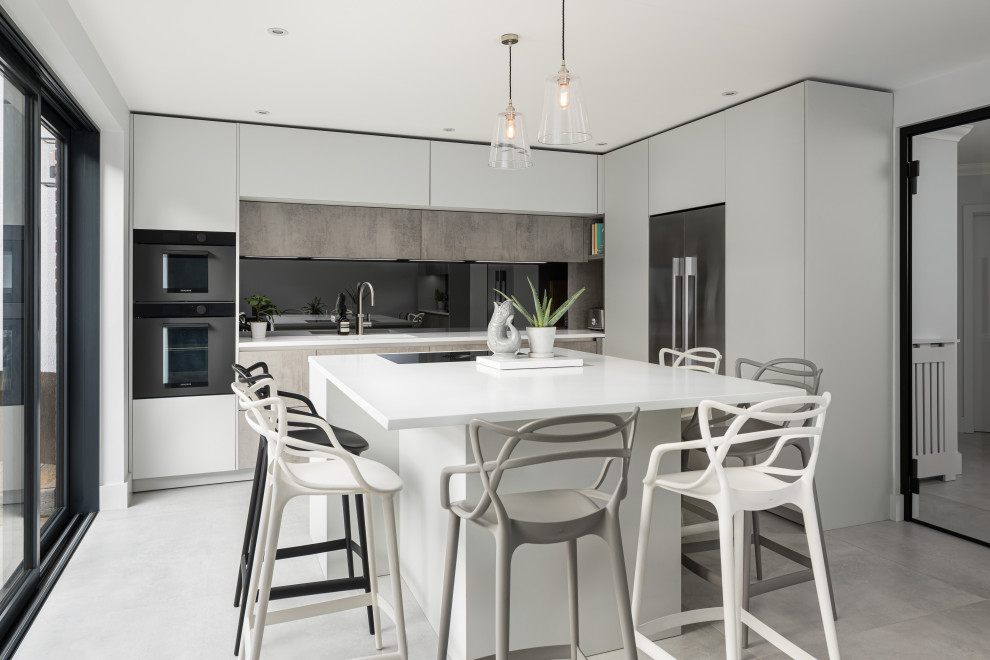 Inspiration for a medium sized contemporary l-shaped kitchen in London with an island, white worktops, flat-panel cabinets, grey cabinets, stainless steel appliances and grey floors.