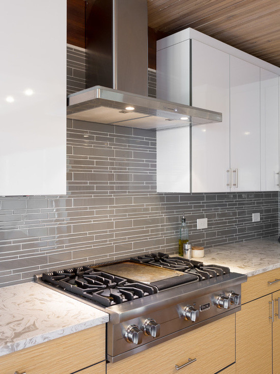 Large modern l-shaped open plan kitchen in Chicago with an undermount sink, flat-panel cabinets, white cabinets, marble benchtops, grey splashback, subway tile splashback, stainless steel appliances, medium hardwood floors and with island.