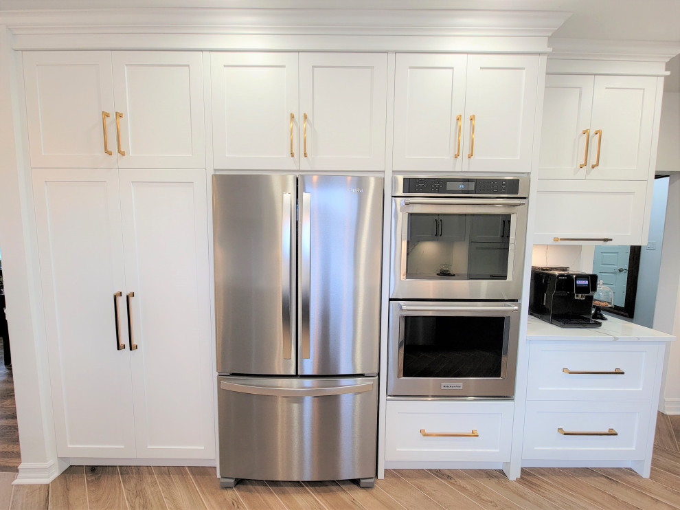 Inspiration for a mid-sized transitional galley porcelain tile and brown floor eat-in kitchen remodel in Montreal with an undermount sink, shaker cabinets, blue cabinets, quartz countertops, white backsplash, quartz backsplash, stainless steel appliances, a peninsula and white countertops