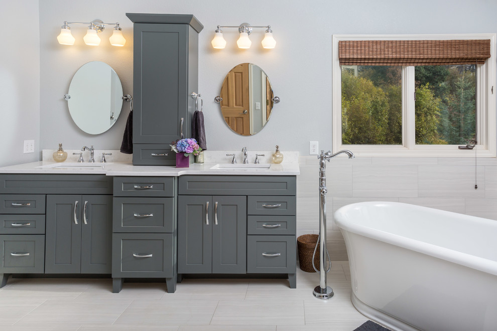 Mid-sized transitional master white tile and porcelain tile porcelain tile freestanding bathtub photo with an undermount sink, shaker cabinets, gray cabinets, quartz countertops, a one-piece toilet and gray walls