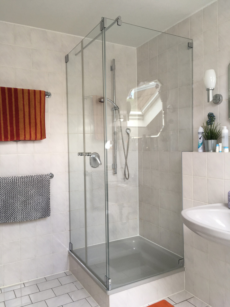 Inspiration för ett litet funkis badrum med dusch, med en hörndusch, en vägghängd toalettstol, grå kakel, porslinskakel, vita väggar, klinkergolv i porslin, ett väggmonterat handfat, vitt golv och dusch med gångjärnsdörr