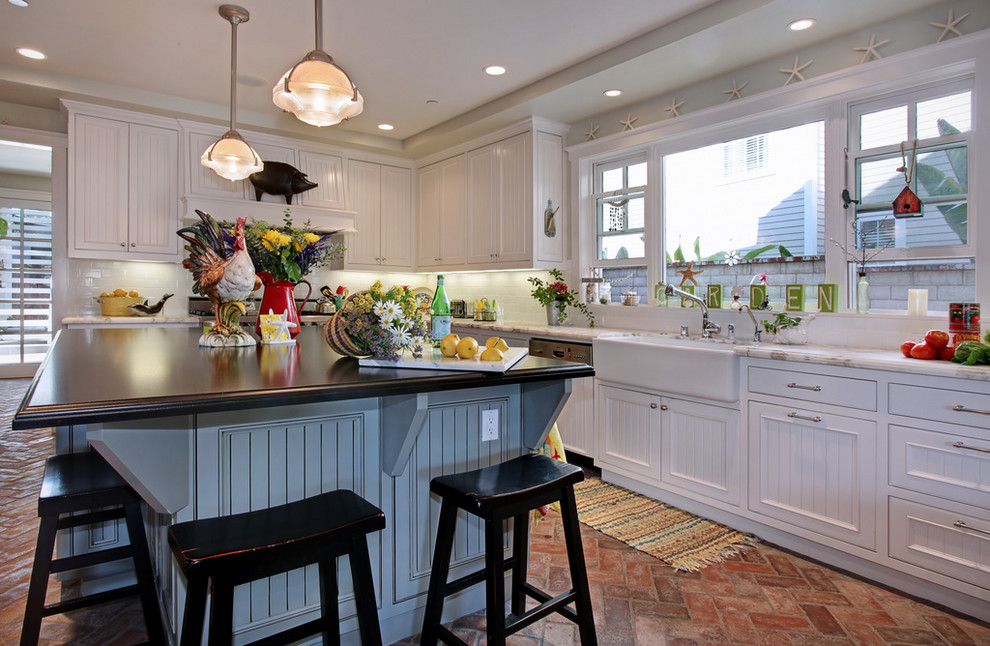 This is an example of a beach style kitchen in Orange County with brick floors.