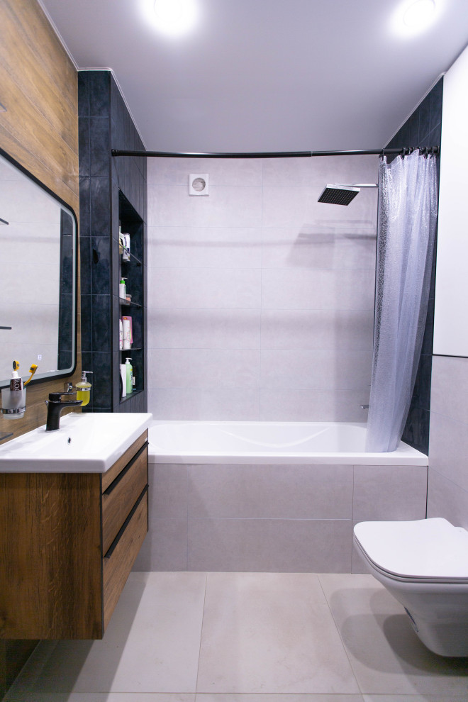 This is an example of a small contemporary master bathroom in Other with flat-panel cabinets, medium wood cabinets, an alcove tub, a shower/bathtub combo, a wall-mount toilet, blue tile, wood-look tile, beige walls, porcelain floors, a drop-in sink, grey floor, a shower curtain, a single vanity and a floating vanity.