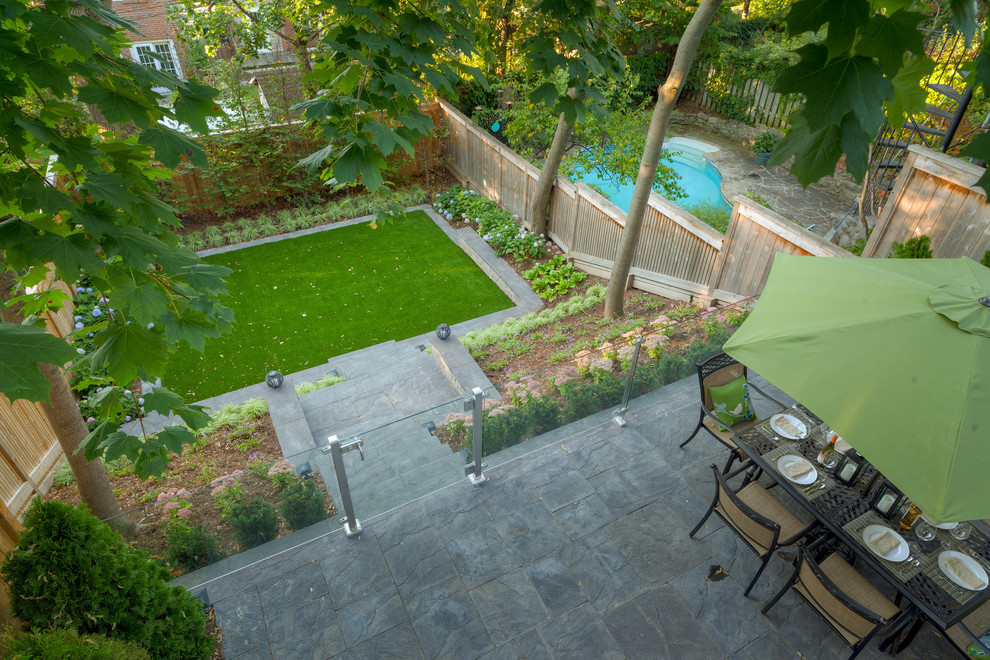 Inspiration for a mid-sized modern backyard full sun formal garden for summer in Toronto with a retaining wall and concrete pavers.