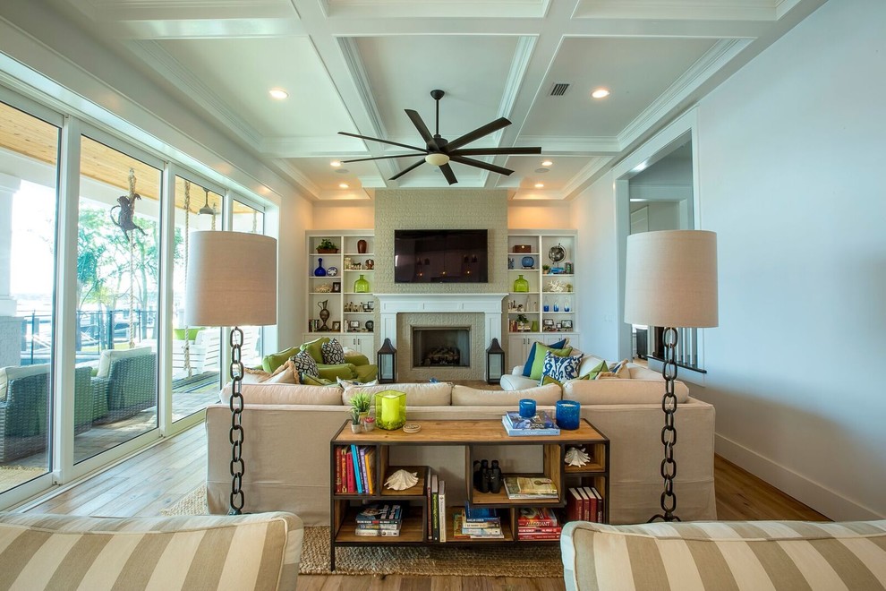 Inspiration for a large beach style open concept living room in Jacksonville with white walls, light hardwood floors, a standard fireplace, a brick fireplace surround and a wall-mounted tv.