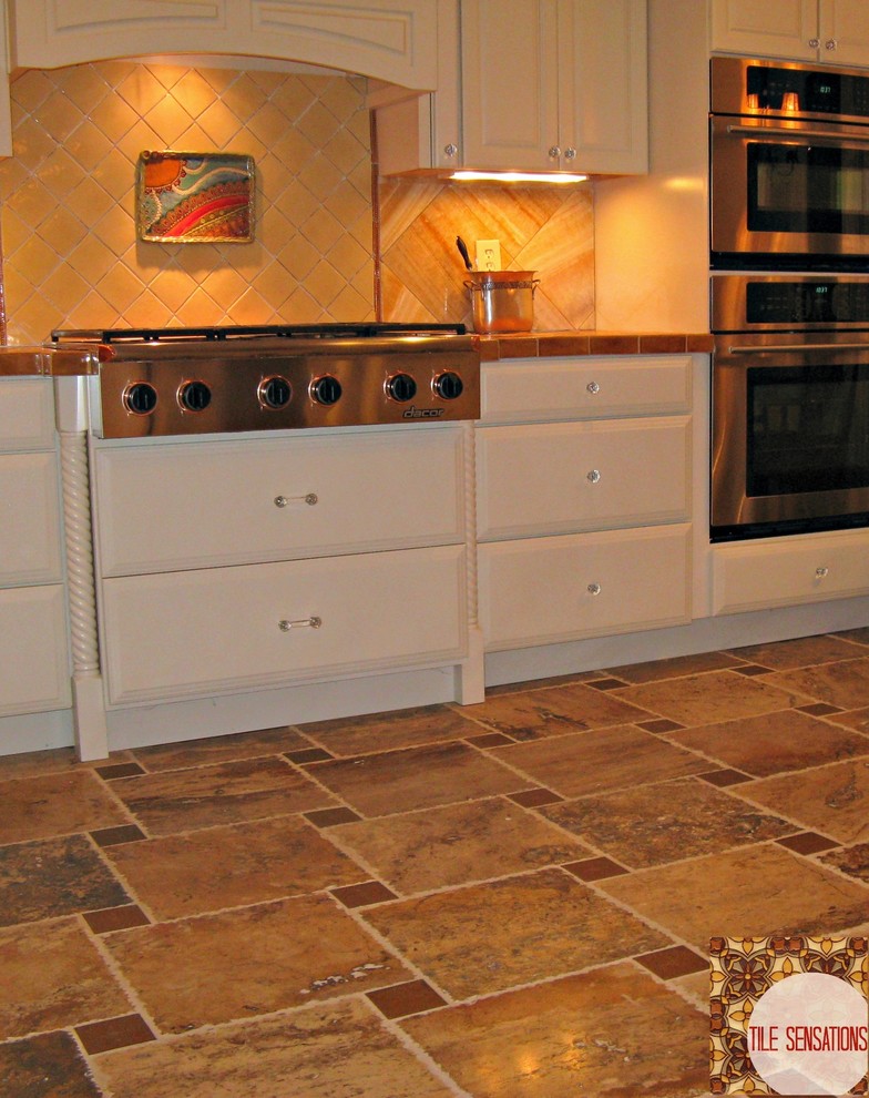 Inspiration for a large transitional travertine floor kitchen remodel with raised-panel cabinets, white cabinets, tile countertops, brown backsplash, stone tile backsplash and stainless steel appliances