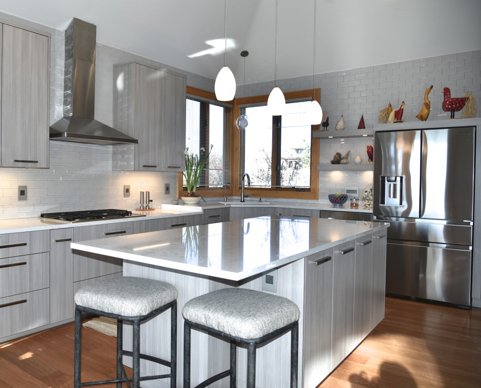 Example of a large transitional u-shaped medium tone wood floor and brown floor enclosed kitchen design in Denver with a single-bowl sink, flat-panel cabinets, gray cabinets, quartzite countertops, ceramic backsplash, stainless steel appliances, an island and white countertops