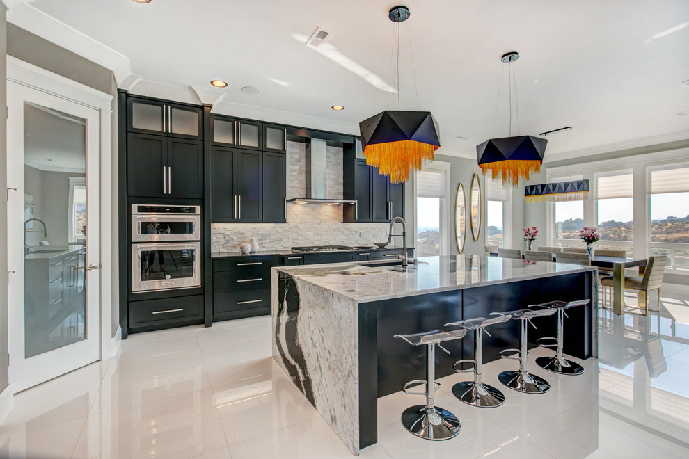 Example of a large trendy l-shaped white floor open concept kitchen design in Seattle with an undermount sink, shaker cabinets, black cabinets, granite countertops, white backsplash, stone tile backsplash, stainless steel appliances and an island