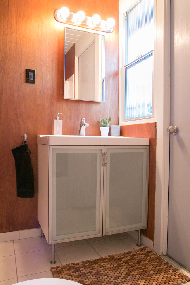 This is an example of a midcentury bathroom in San Francisco with glass-front cabinets, grey cabinets, a drop-in tub, a shower/bathtub combo, a one-piece toilet, white tile, ceramic tile, brown walls, ceramic floors, a console sink, white floor and a shower curtain.