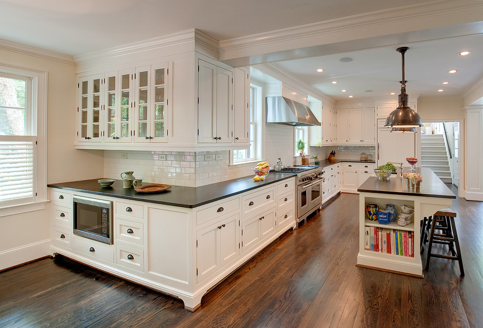 Open concept kitchen - large transitional l-shaped medium tone wood floor open concept kitchen idea in Atlanta with a farmhouse sink, beaded inset cabinets, white cabinets, granite countertops, white backsplash, porcelain backsplash, paneled appliances and an island