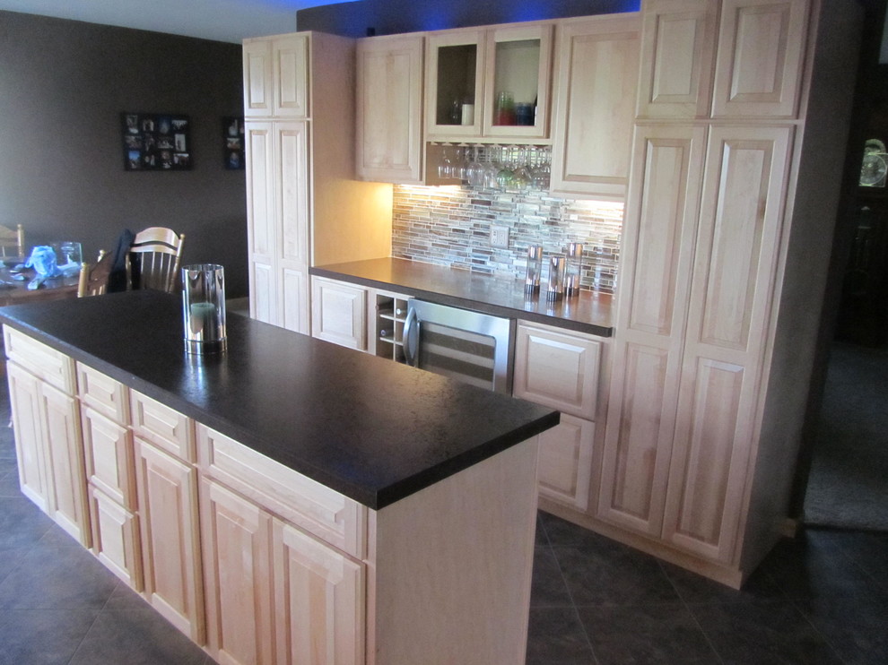 Example of a mid-sized transitional galley porcelain tile and beige floor enclosed kitchen design with a double-bowl sink, raised-panel cabinets, light wood cabinets, granite countertops, beige backsplash, porcelain backsplash, stainless steel appliances and an island