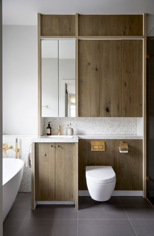 Design ideas for a large scandinavian kids bathroom in London with recessed-panel cabinets, medium wood cabinets, a freestanding tub, brown tile, ceramic tile, terrazzo benchtops, grey benchtops, a single vanity and a built-in vanity.