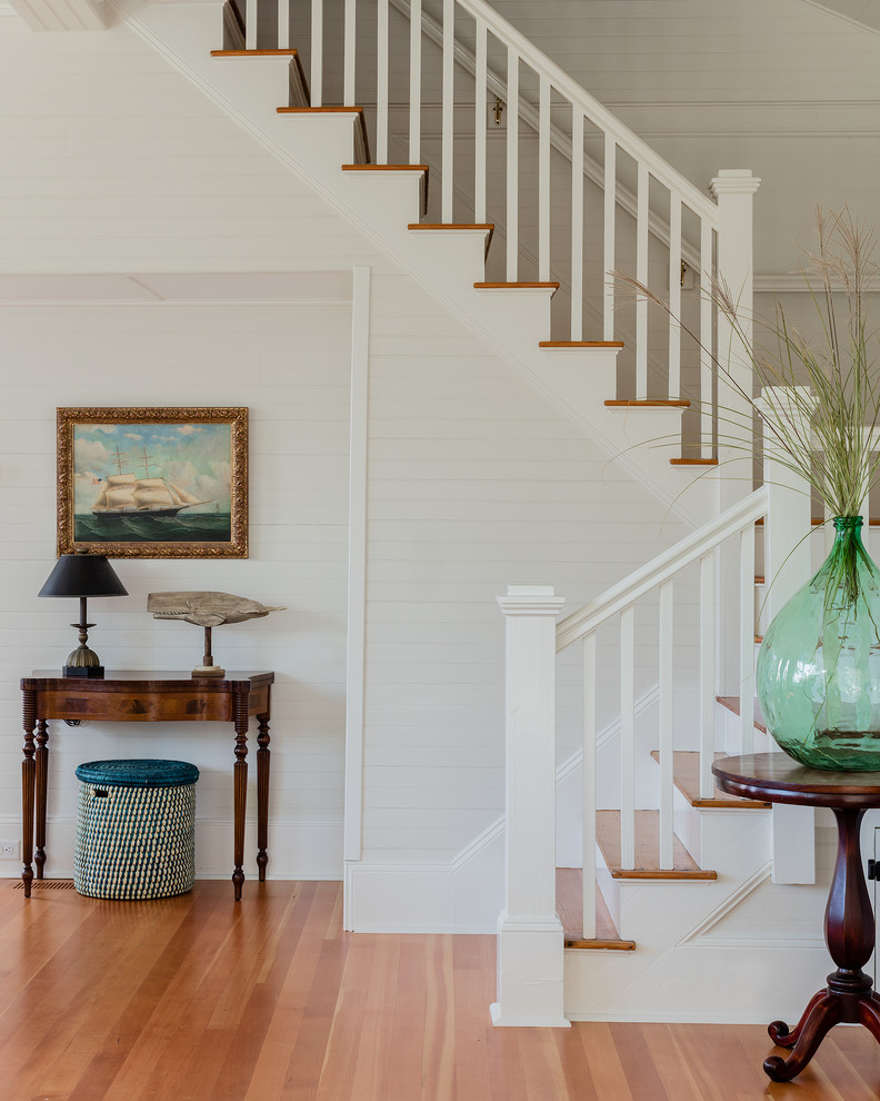 This is an example of a beach style wood u-shaped staircase in Boston with painted wood risers and wood railing.
