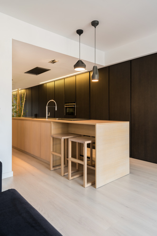 Photo of a large contemporary galley kitchen in Valencia with a drop-in sink, flat-panel cabinets, black cabinets, wood benchtops, panelled appliances, with island, beige floor and beige benchtop.