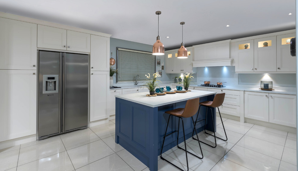 Inspiration for a transitional l-shaped kitchen in Dublin with recessed-panel cabinets, blue cabinets, blue splashback, stainless steel appliances, with island, white floor and white benchtop.