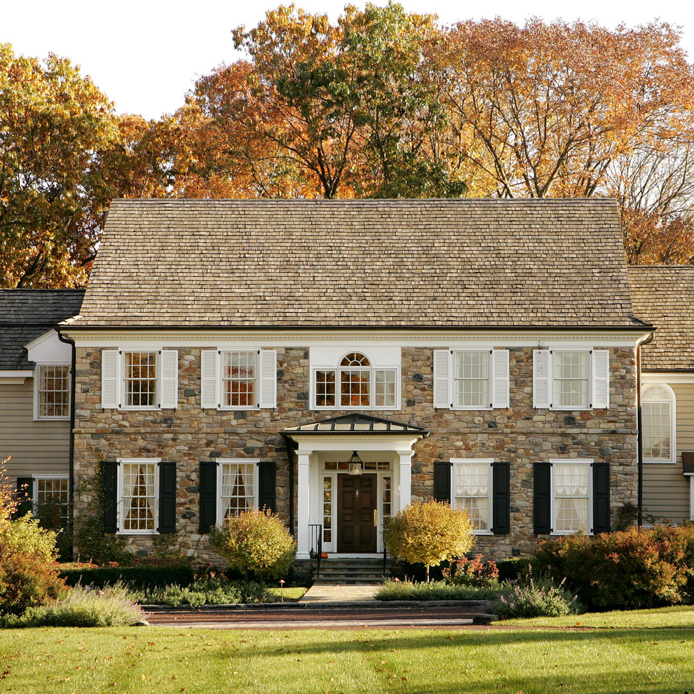 Traditional three-storey exterior in Philadelphia with stone veneer and a gable roof.