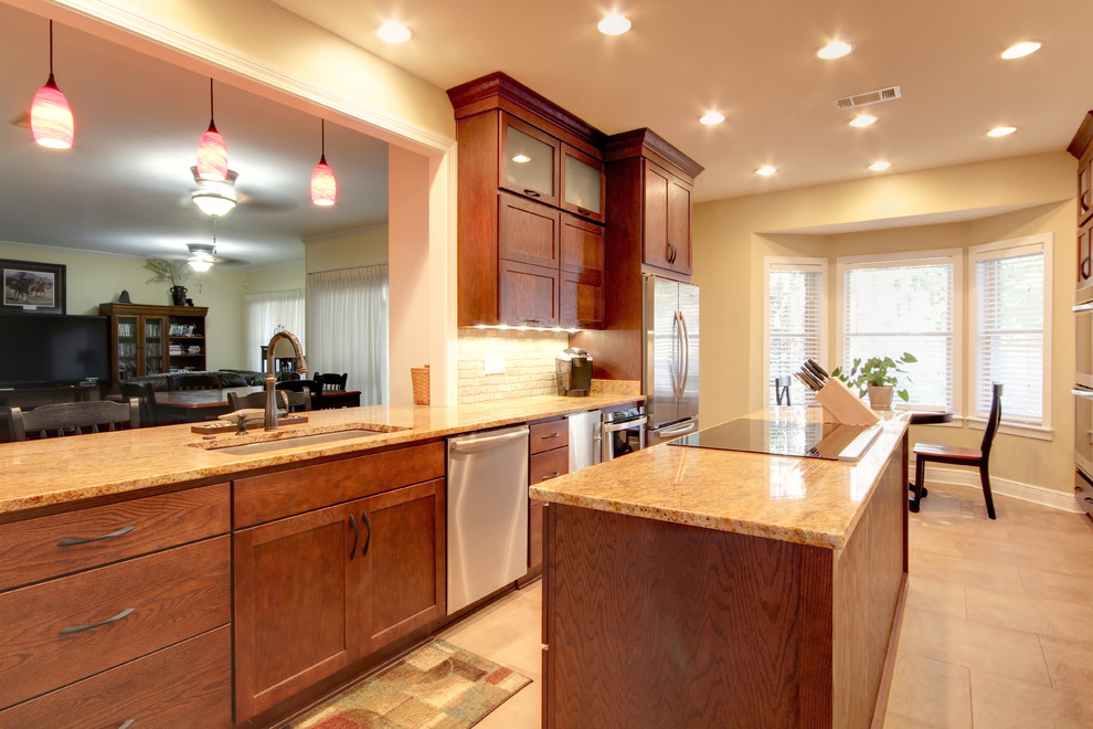Inspiration for a transitional eat-in kitchen remodel in Miami with an undermount sink, shaker cabinets, brown cabinets, granite countertops, beige backsplash, stone tile backsplash and stainless steel appliances