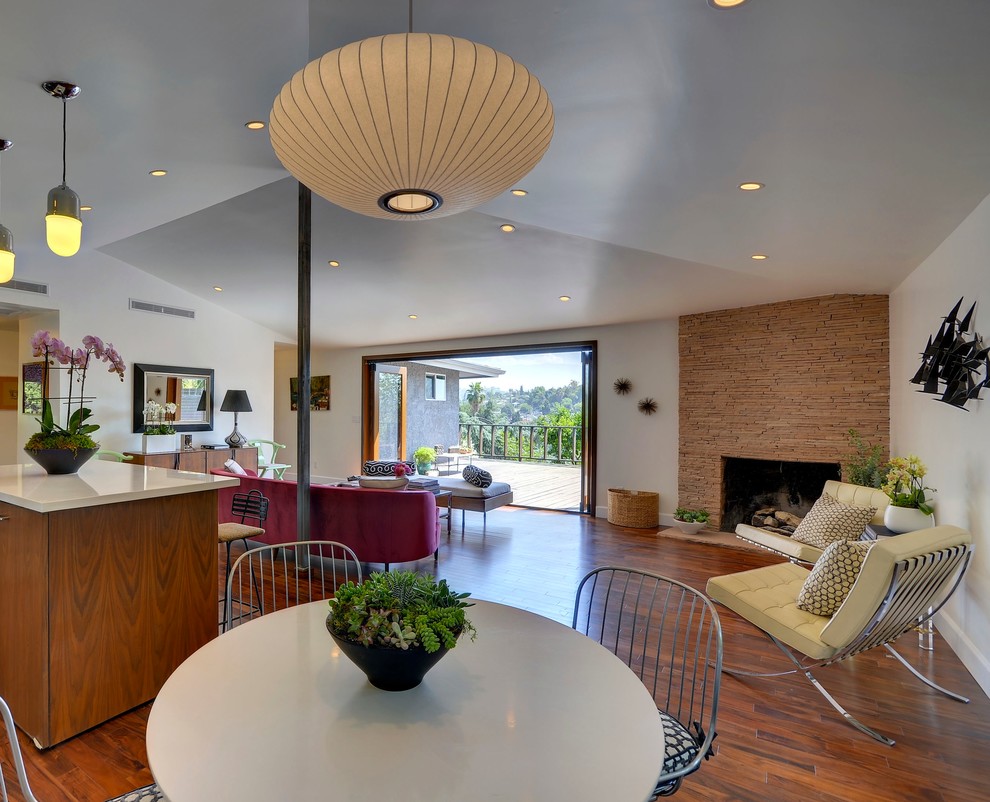 Great room - mid-century modern great room idea in Los Angeles with a stone fireplace