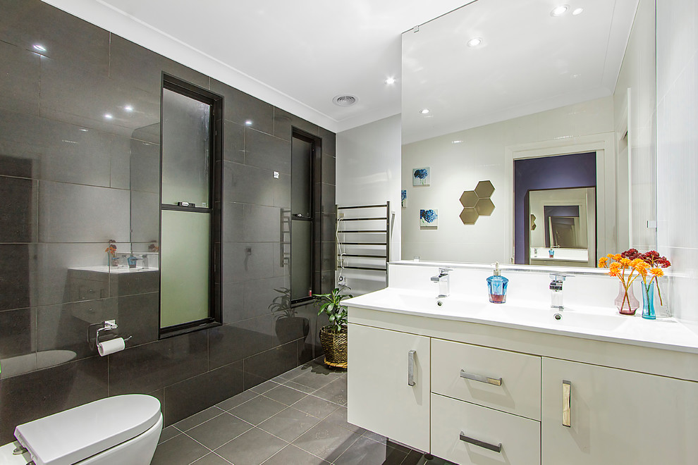 Photo of a large master bathroom in Sydney with flat-panel cabinets, white cabinets, a double shower, a one-piece toilet, black and white tile, porcelain tile, black walls, porcelain floors, a wall-mount sink and solid surface benchtops.