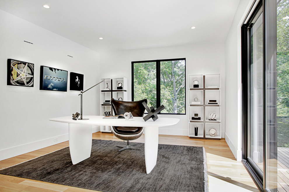 Bild på ett stort funkis arbetsrum, med vita väggar, ljust trägolv och ett fristående skrivbord