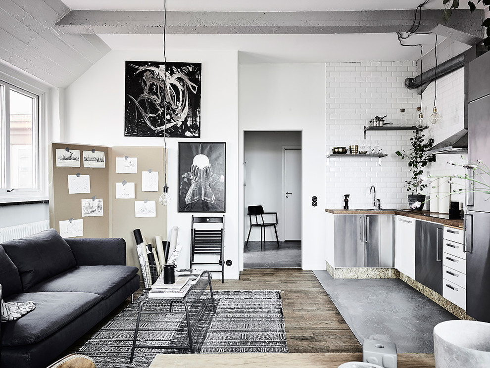 Photo of a large industrial l-shaped open plan kitchen in Gothenburg with stainless steel cabinets, wood benchtops, porcelain splashback, stainless steel appliances, concrete floors and no island.