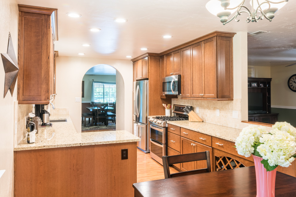 Photo of a mid-sized contemporary galley eat-in kitchen in Sacramento with an undermount sink, recessed-panel cabinets, medium wood cabinets, marble benchtops, beige splashback, ceramic splashback, stainless steel appliances, light hardwood floors and no island.