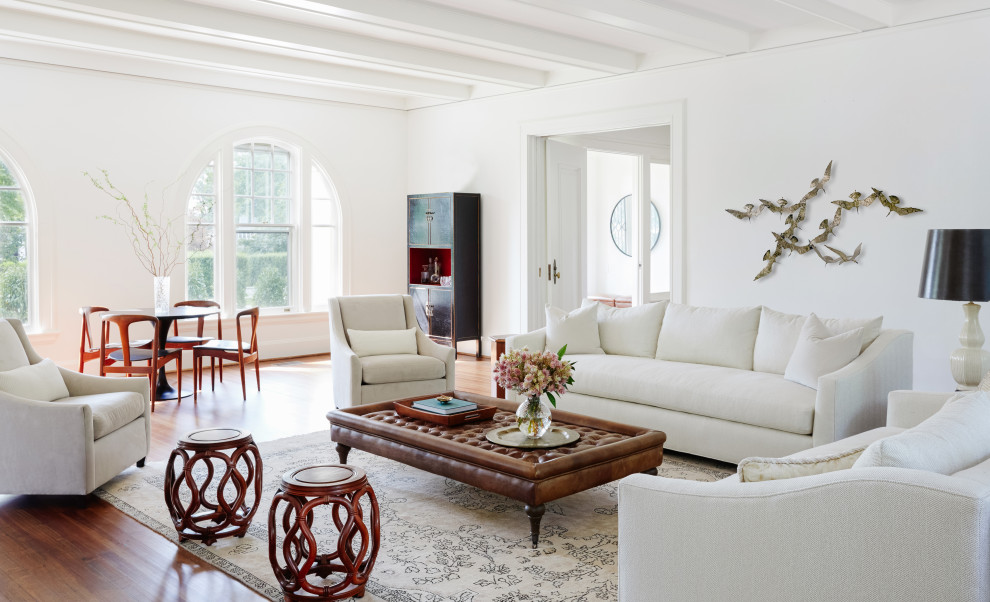 Example of a transitional medium tone wood floor and exposed beam living room design with white walls
