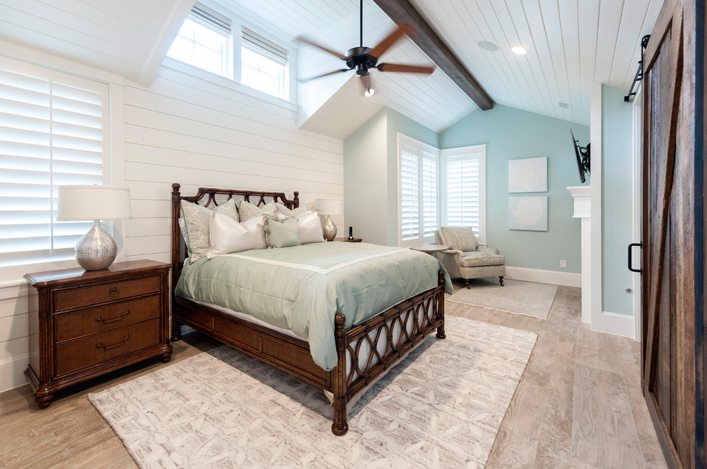 Large country master bedroom in Houston with blue walls, light hardwood floors, a standard fireplace, beige floor, timber and planked wall panelling.