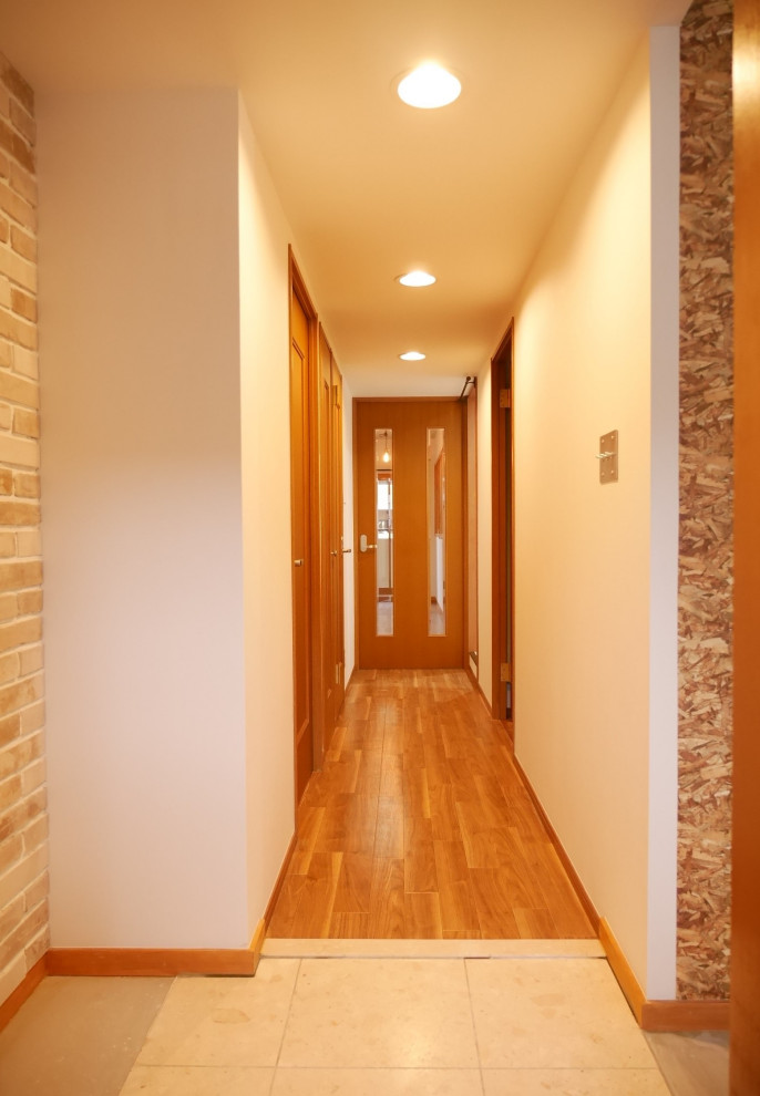 Photo of a small midcentury entry hall in Other with beige walls, ceramic floors, a single front door, white floor, wallpaper and brick walls.