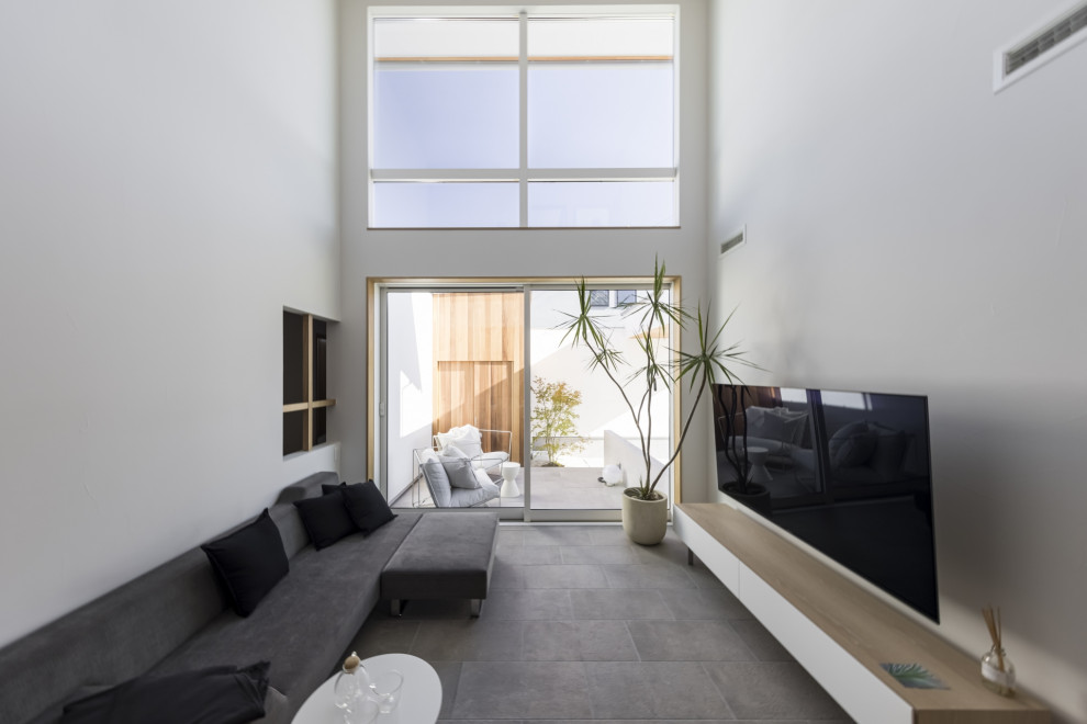 Idee per un soggiorno moderno aperto con pareti bianche, pavimento con piastrelle in ceramica, nessun camino, TV a parete e pavimento grigio