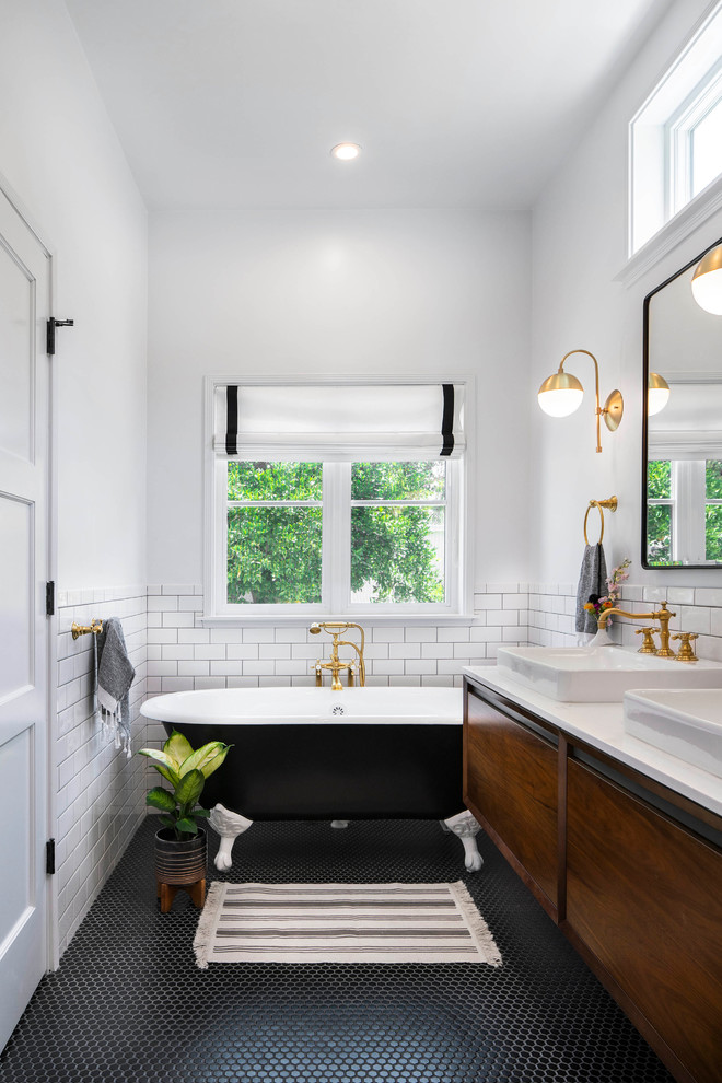 Inspiration for a mid-sized transitional master bathroom in Los Angeles with flat-panel cabinets, a claw-foot tub, white tile, ceramic tile, white walls, mosaic tile floors, a vessel sink, engineered quartz benchtops, black floor, white benchtops and medium wood cabinets.