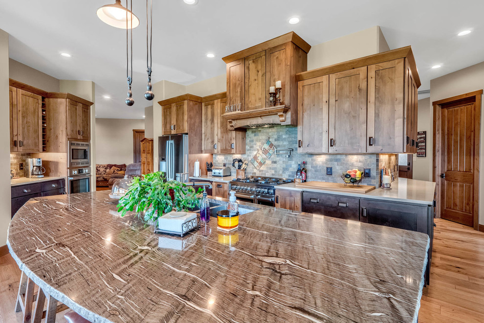 Photo of a mid-sized country kitchen in Denver with an undermount sink, recessed-panel cabinets, dark wood cabinets, granite benchtops, multi-coloured splashback, stone tile splashback, stainless steel appliances, medium hardwood floors, with island, multi-coloured floor and multi-coloured benchtop.