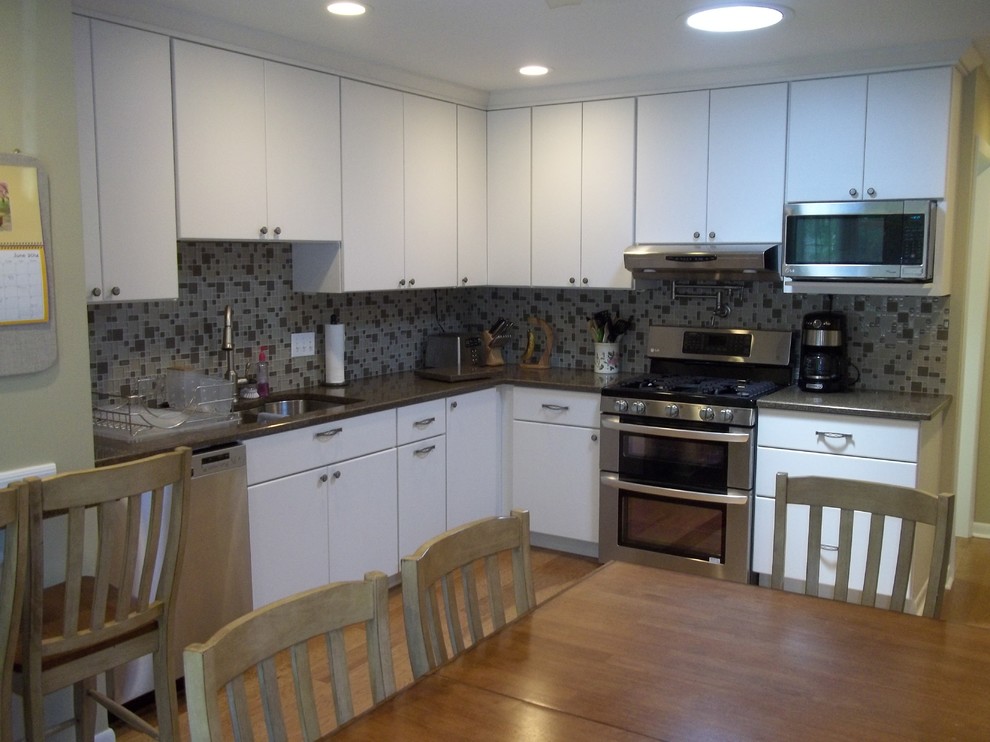 This is an example of a mid-sized modern l-shaped eat-in kitchen in Chicago with an undermount sink, flat-panel cabinets, white cabinets, quartz benchtops, beige splashback, glass tile splashback, stainless steel appliances, medium hardwood floors and no island.
