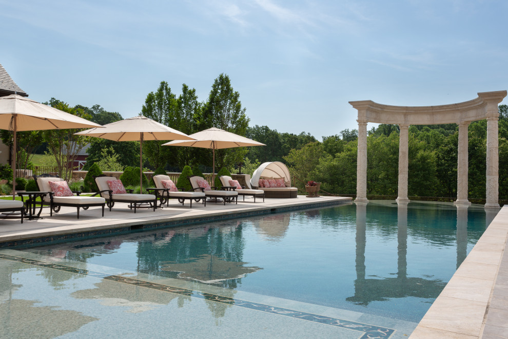 Expansive traditional backyard rectangular infinity pool in DC Metro with a hot tub and natural stone pavers.