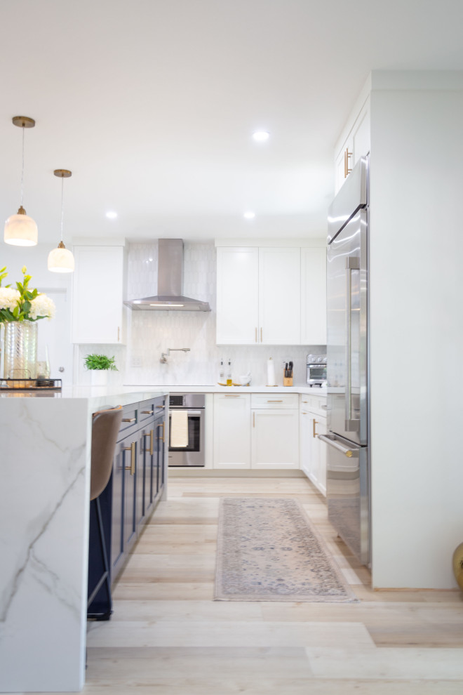 Transitional eat-in kitchen in Miami with a single-bowl sink, shaker cabinets, white cabinets, quartz benchtops, white splashback, stone tile splashback, stainless steel appliances, vinyl floors, with island, beige floor and white benchtop.
